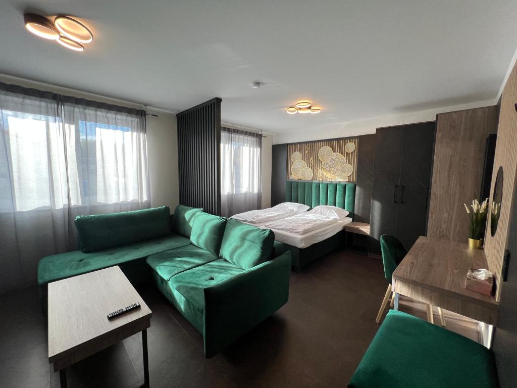 Ein modern gestaltetes Hotelzimmer mit einem grünen Samtsofa und passenden Stühlen, einem Doppelbett mit hölzernem Kopfteil und integrierter Beleuchtung, dargestellt durch einen renommierten Hotelmöbel Hersteller.